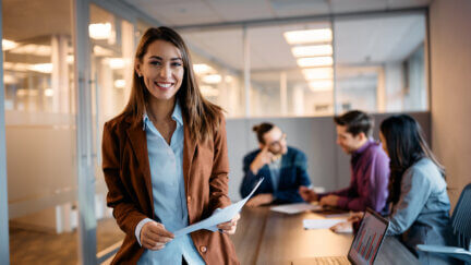 product manager smiles as her team meets behind her