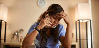 stressed filipina nurse taking phonecall at home